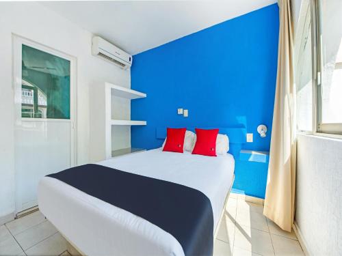 a blue and white bedroom with a bed with red pillows at Capital O Hotel El Mejicano, Acapulco in Acapulco