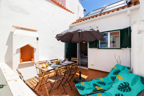 a patio with a table and chairs and an umbrella at Harbour House in Ericeira