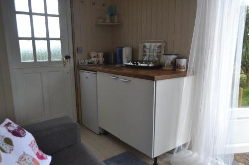 eine Küche mit einer Theke, einem Stuhl und einem Fenster in der Unterkunft Peaceful Shepherd's Hut next to Horse Field in Morpeth
