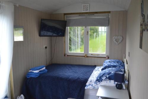 a small bedroom with a bed and a window at Peaceful Shepherd's Hut next to Horse Field in Morpeth
