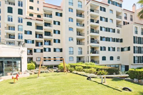 a playground in front of a large apartment building at Sea Front Family Apartment in Parede