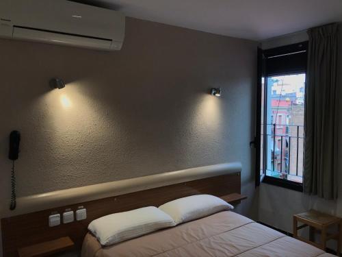 1 dormitorio con cama, ventana y luces en Hostal Radio Barcelona, en Barcelona