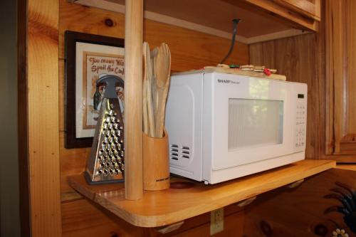 a microwave sitting on a shelf next to some knives at Country Road Cabins in Hico