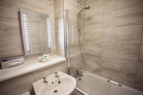 uma casa de banho com um chuveiro, um lavatório e uma banheira em Strathaven Hotel em Strathaven