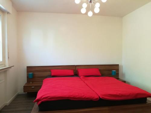 a bedroom with a red bed with two red pillows at Ferienwohnung am Wiedenberg in Arnsberg