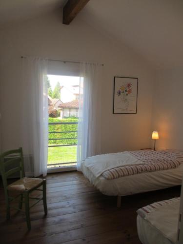 une chambre avec deux lits et une grande fenêtre dans l'établissement Les Verdurettes, à Soustons