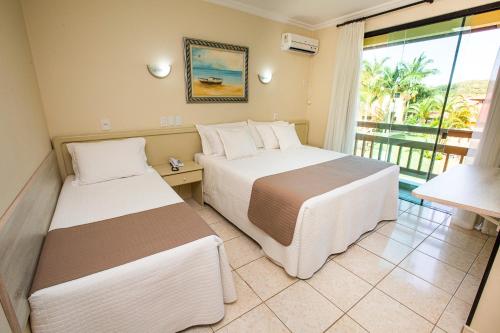 um quarto de hotel com duas camas e uma varanda em Águas de Palmas Resort em Governador Celso Ramos