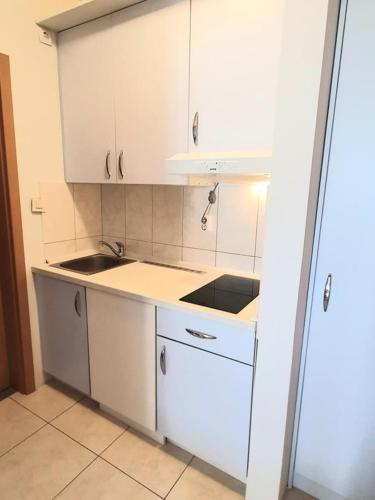 a small kitchen with white cabinets and a sink at apartments oaza, vrsi mulo in Vrsi
