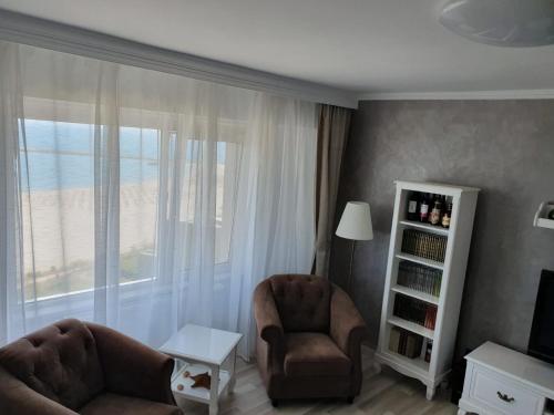 een woonkamer met 2 stoelen en een groot raam bij Apartament Plaja Golful Pescarilor in Constanţa