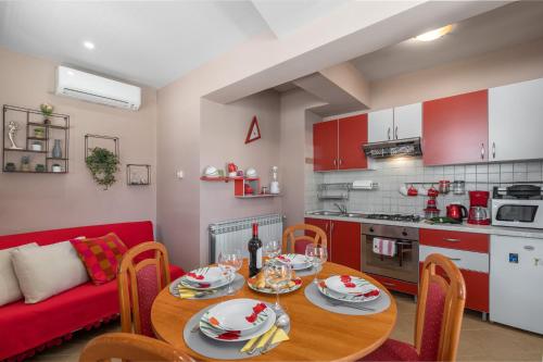 a kitchen and dining room with a table and a red couch at Apartments Nono in Poreč