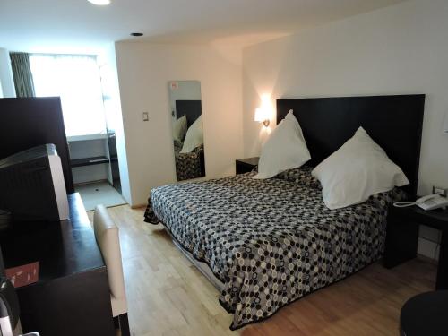 ein Hotelzimmer mit einem Bett und einem Spiegel in der Unterkunft Hotel Granada in Puebla