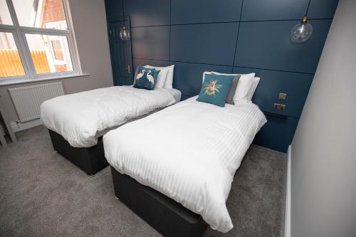 two beds in a room with blue walls at Lynwood House in Southport