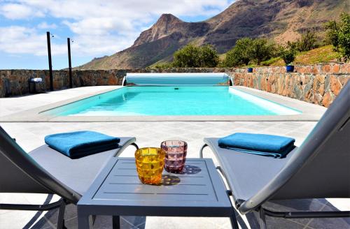 Una mesa y sillas junto a una piscina. en Villa Fataga - Unique villa with heated pool, en Fátaga
