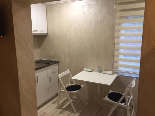 eine Küche mit einem weißen Tisch und 2 Stühlen in der Unterkunft Feeling Home 1 Room Studio - Dorobanti in Buzău