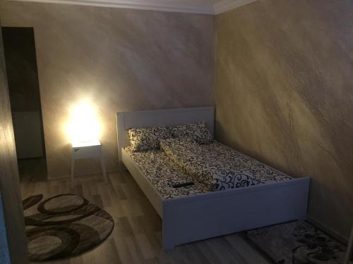 Feeling Home 1 Room Studio - Dorobanti في Buzău: سرير صغير في غرفة صغيرة بها مصباح