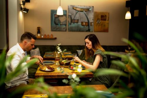 mężczyzna i kobieta siedzący przy stole jedzący jedzenie w obiekcie Hotel Vineyard Inn - Szőlőskert w mieście Nagykanizsa
