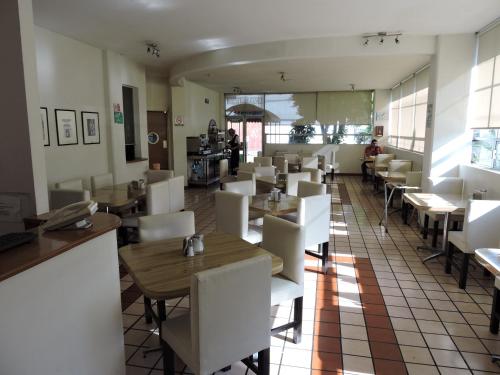 Hotel Granada في بوبلا: غرفة طعام مع كراسي بيضاء وطاولات في مطعم