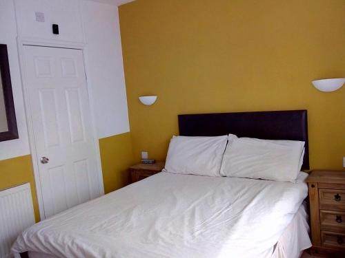 a bedroom with a white bed and a yellow wall at Seamore Guest House in Great Yarmouth