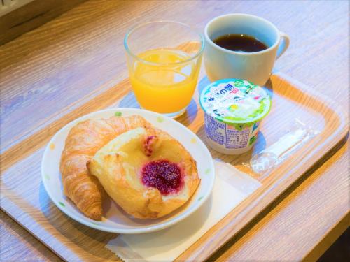 um prato de pequeno-almoço com um produto de pastelaria e uma chávena de café e sumo de laranja em SHIN YOKOHAMA SK HOTEL - Smoking - Vacation STAY 86105 em Yokohama