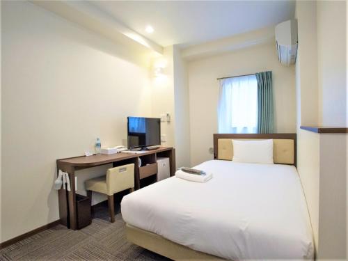 横浜市にあるSHIN YOKOHAMA SK HOTEL - Smoking - Vacation STAY 86105のベッドと机とパソコンが置かれたホテルの部屋