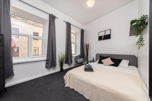 a white bedroom with a bed and two windows at The house Vilnius in Vilnius