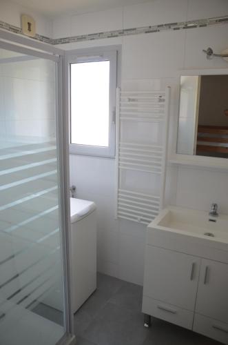 a white bathroom with a sink and a mirror at Spacieux T2 vue mer panoramique Le Brusc in Six-Fours-les-Plages