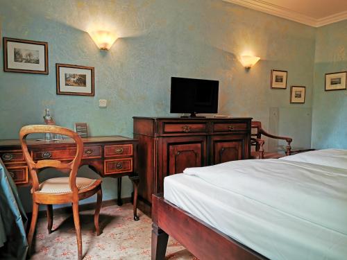 a bedroom with a bed and a desk with a television at Hotel Altmünchen by Blattl in Munich