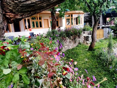 a garden with flowers in front of a house at Mountain Refuge Guest House in Baltit