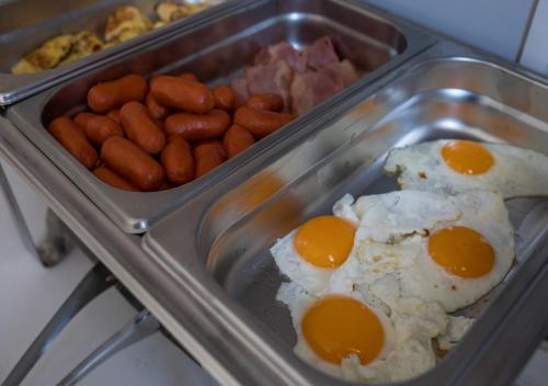 a tray of eggs and sausages and other breakfast foods at Niriides Hotel Apartments in Symi