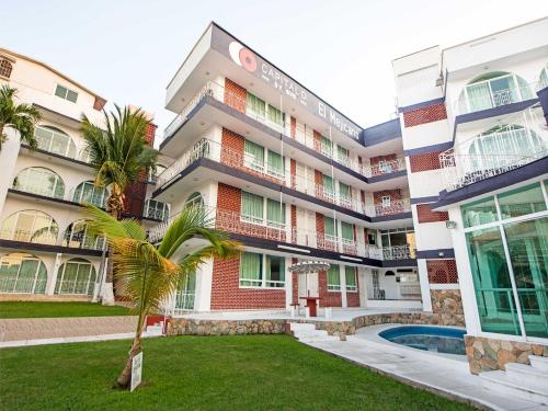 a building with a palm tree in front of it at Capital O Hotel El Mejicano, Acapulco in Acapulco