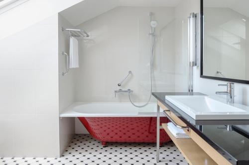 La salle de bains est pourvue d'une baignoire rouge et d'un lavabo. dans l'établissement Neiburgs Hotel, à Riga