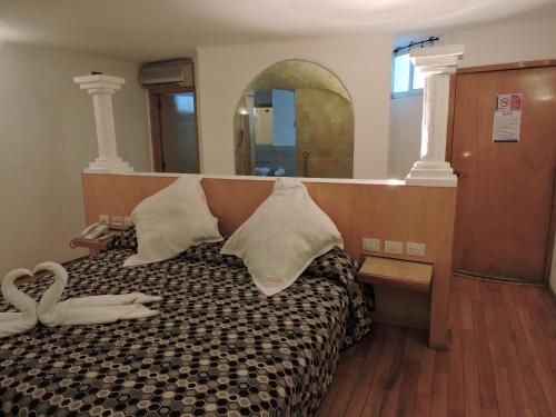Un dormitorio con una cama con almohadas y un espejo. en Motel Mykonos, en Puebla