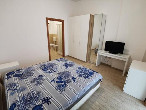 a bedroom with a bed and a desk with a television at All' Ombra del Faro - Mini Apartments in Taranto