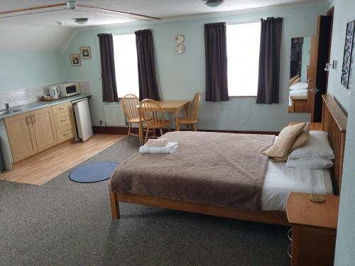 a bedroom with a bed and a table and a kitchen at Malin House Hotel in Saundersfoot