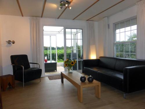 a living room with a black couch and a table at Vakantiehuis Appelvink, Toplocatie in bosrijke omgeving in Oisterwijk