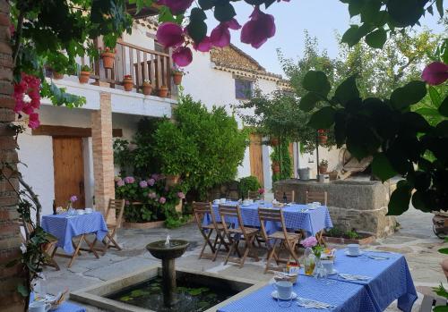 a garden with blue tables and chairs and a fountain at Hotel Labranza in San Martín de Valdeiglesias