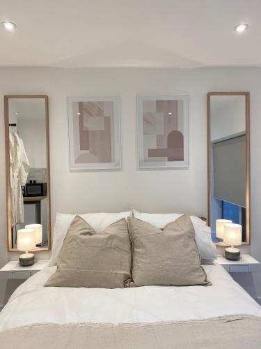 a bedroom with a white bed with three mirrors at Seaporth Studio St Ives in St Ives