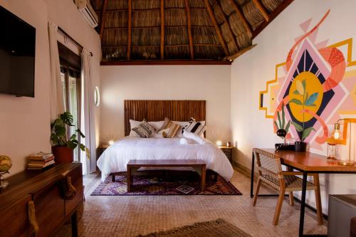 a bedroom with a bed, table, and a painting on the wall at Selina Sayulita in Sayulita