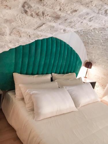 a white bed with a green headboard and white pillows at Ariad Collection in Ostuni