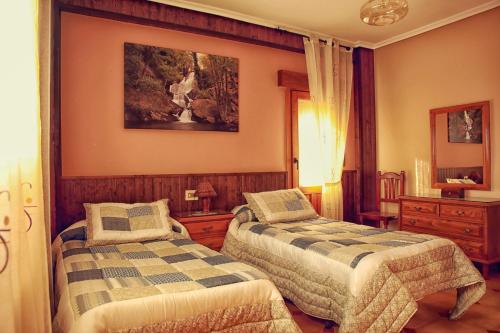 a bedroom with two beds and a painting on the wall at Apartamento Turistico Rio Jerte in Navaconcejo