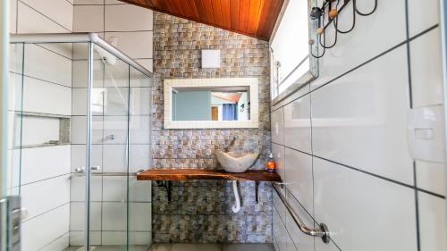 a bathroom with a mirror and a sink on a shelf at Chalé Bosque Do Barreiro in Araxá