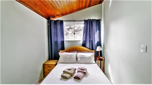 a small bedroom with a bed with two shoes on it at Chalé Bosque Do Barreiro in Araxá