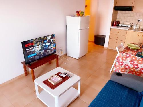 a living room with a table and a white refrigerator at Beach Front Apartment in Larnaka