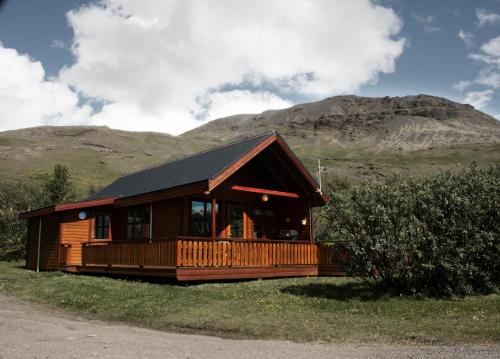 a wooden cabin with mountains in the background at Ásólfsskáli Cottage in Ásólfsskáli