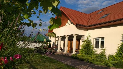 biały dom z czerwonym dachem w obiekcie Pensjonat Poranna Rosa w mieście Grabowiec