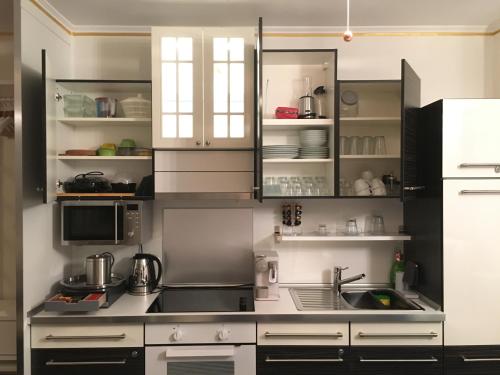 a kitchen with white cabinets and a sink at E&M Apartments Düsseldorf in Düsseldorf