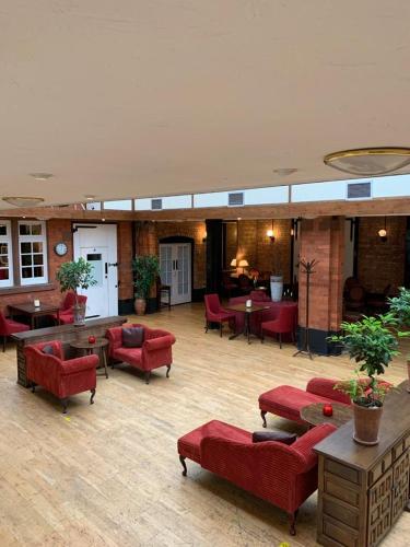 a lobby with red couches and tables and chairs at The Carre Arms Hotel & Restaurant in Sleaford