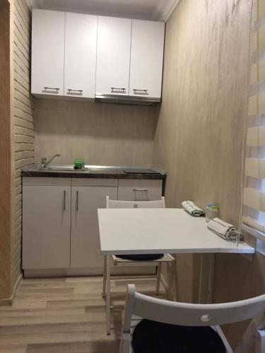 eine Küche mit weißen Schränken sowie einem weißen Tisch und Stühlen in der Unterkunft Feeling Home 1 Room Studio - Dorobanti in Buzău