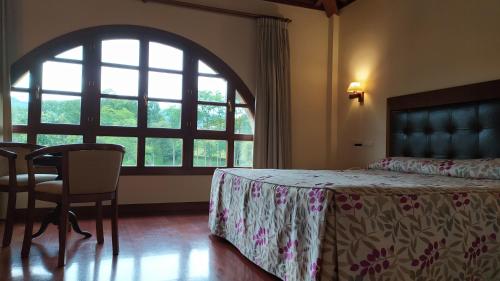 a bedroom with a bed and a table and a window at Hotel Valle Las Luiñas in Soto de Luiña