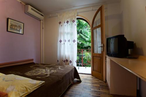 een slaapkamer met een bed, een televisie en een raam bij Romantic room with balcony in Lovran
